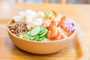 A gourmet poke bowl featuring scallops, shrimp, potato, cucumber, and quinoa rice, drizzled with parmesan cheese dressing and mustard vinaigrette. The dish presents a refreshing summer flavor with a b