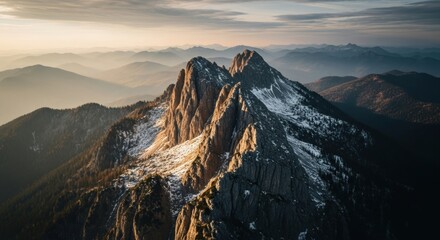 Epic mountain range at golden hour sunrise. Jagged rocky peaks with snow cover. Aerial perspective of a vast alpine wilderness. Metaphor for ambition journey and success