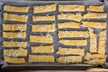 Uncooked cheese sticks on parchment lined tray, top view