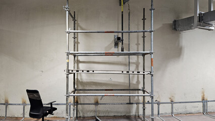 Metal scaffolding structure with black office chair in industrial workshop ready for maintenance work