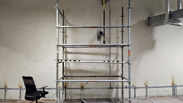 Metal scaffolding structure with black office chair in industrial workshop ready for maintenance work