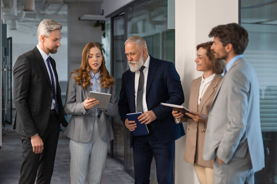 Successful businesspeople working in a coworking space working with digital tablet discussing strategy and business plan in modern office.