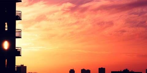 Stunning orange sunset over city skyline with silhouette of apartment building, creating a warm and peaceful urban landscape at dusk
