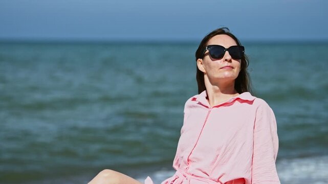 Young woman in sunglasses relaxing by Baltic Sea shore on sunny day