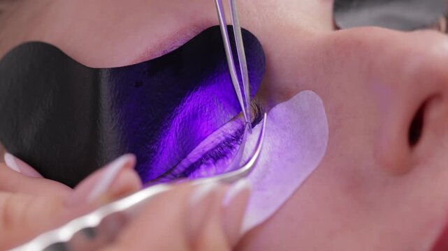 Caucasian young female undergoing professional eyelash led extension procedure, modern Beauty treatment.