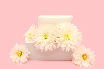 White plastic container on a podium with white flowers.