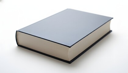 A closed book with a gray cover and thick white pages laying on a white surface in soft light