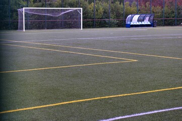 Green soccer field with goal and bench in a peaceful setting during a calm afternoon