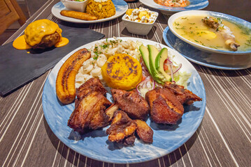 A bowl of green plantain ball soup reveals large green plantain dumplings stuffed with meat, in a peanut broth with yucca and vegetables.
