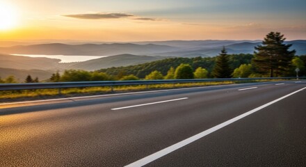 Fototapeta premium A highway stretches into the distance, with a mountain range and a body of water in the background. The scene is bathed in warm, golden light, creating a serene and picturesque atmosphere.