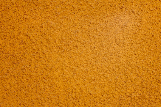 Turmeric powder texture on warm orange surface, a versatile spice for cooking and health