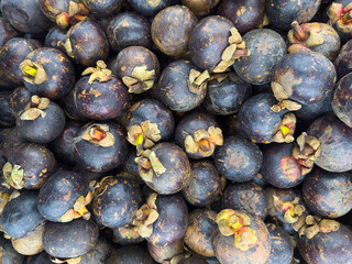 Fresh mangosteens piled together in a vibrant market setting
