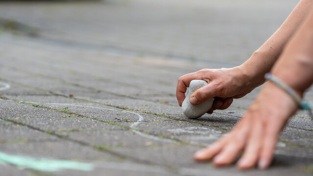 Eine Hand mit Kreide bemalt einen Fu&szlig;weg