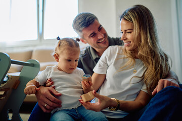 Parents and toddler daughter happily playing with educational wooden toys, enjoying quality time...