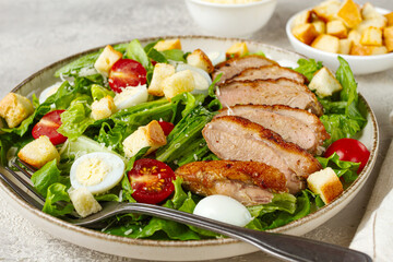 Caesar salad, with duck breast, on a light plate, on a light background, homemade, no people,