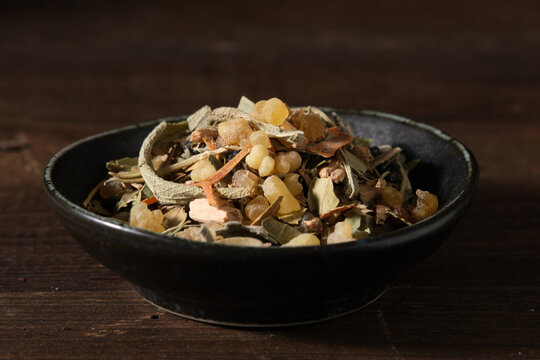 Herbal incense mix in black bowl on wooden table