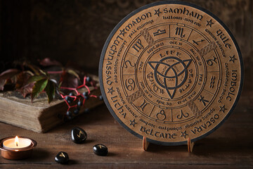 Mystic Wheel of the Year with runes and ritual items on a wooden table. Spiritual and pagan concept.