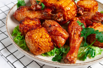 Fried chicken drumsticks, Mexican style, with corn, on a plate, close-up,