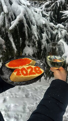A sandwich 2026 with red caviar and a glass of champagne against the backdrop of a snowy Christmas tree.