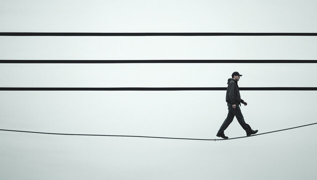 Tightrope Person Walking Jacket Cap Low Angle White Background Black Lines Diagonal Pattern Somber Contemplative Balance Minimalism Generative AI