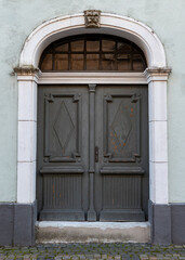 Ornate old town doors marked by time, featuring intricate details and weathered textures. The image reflects historical architecture, craftsmanship, and the quiet charm of aged elegance.