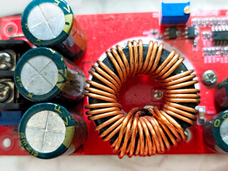 Close-up of an electronic circuit board with copper coil inductor, capacitors, and components on a...
