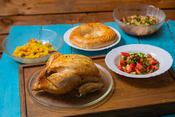 Couscous with dried hands and turmeric, whole baked chicken on a wooden tray