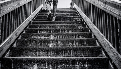 Person ascending outdoor stairs in black and white, leading to an unknown destination