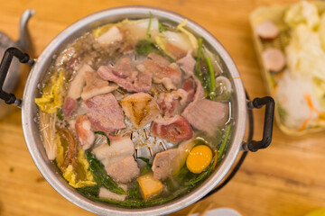 Thai traditional hot barbecue pork on grilled aluminium pan with boiling soup. Thai called Moo Krata, barbecue party on wooden table.