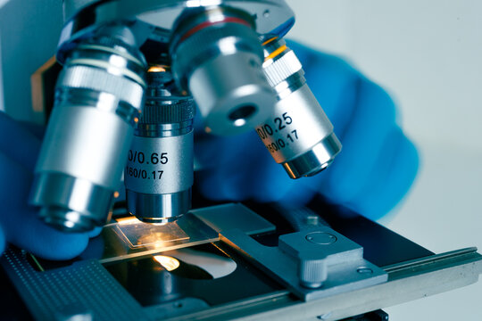 Optical microscope with gloved hands in lab