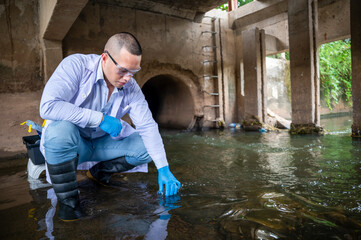 An environmental scientist is holding a glass bottle full of collecting water samples