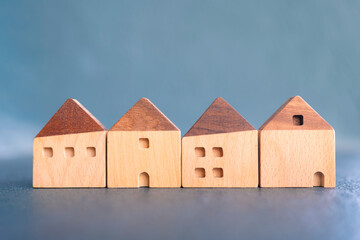Row of miniature wooden houses symbolizing residential real estate market, housing development, investment opportunities, homeownership, rental options, and neighborhood planning.