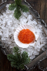 Fresh red salmon roe in a shell on ice. Ice on a metal tray. Spruce branches. Concept of holidays.