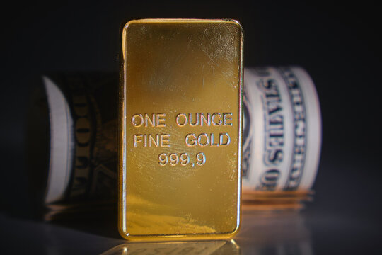 Gold bar and rolled dollar bills representing financial security and investment value