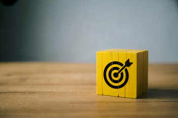 Yellow wooden block with black target symbol on wooden surface goal objective