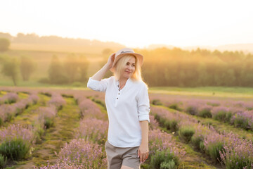Young woman standing on a lavender field with sunrise on the background