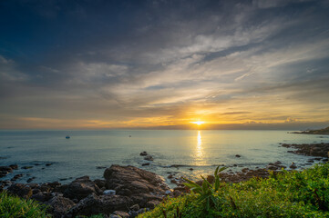 Obraz premium Experience a magical summer sunrise at Waimushan, Keelung, Taiwan. See fishing boats near Keelung Islet under an orange and golden dreamy sky.