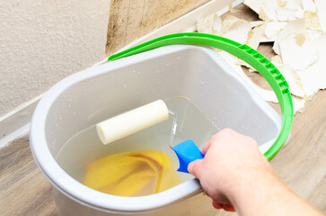 Wallpaper removal with a paint roller in a bucket of water