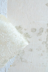 Peeling wallpaper revealing mold and damage on a textured wall surface