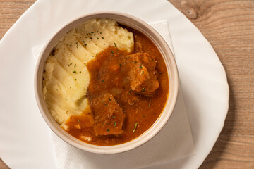 Goulash with beef and carrots with mashed potatoes top view on wooden table
