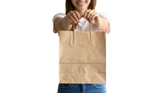 Person in white shirt and jeans smiling, holding a brown paper bag forward