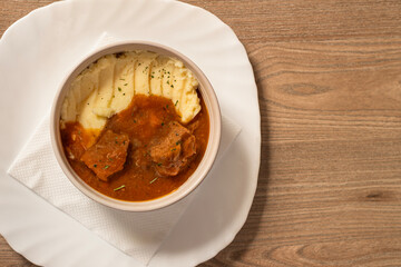 Goulash with beef and carrots with mashed potatoes top view on wooden table