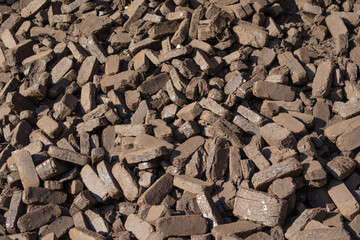 Peat briquettes are arranged on a surface, showcasing their texture and form, used as a renewable energy source in various communities