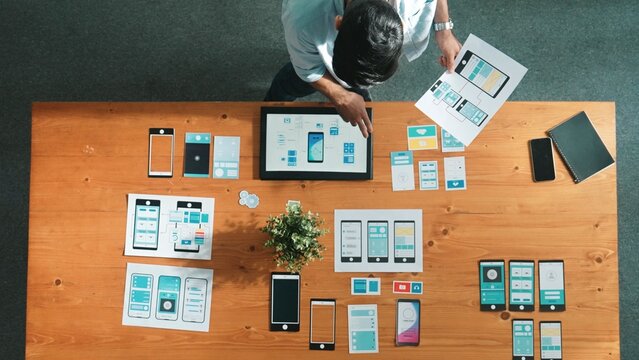 Top view of business man looking and choosing Ux Ui design at meeting room. Skilled developer designing and planning mobile phone interface or software application at creative workplace. Convocation.