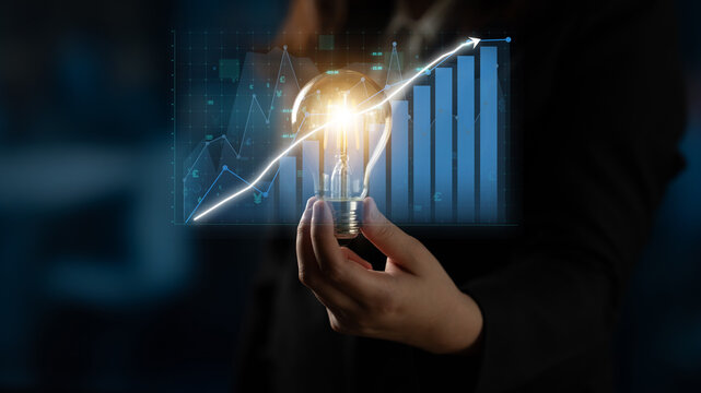 A striking image showcasing a hand holding a glowing light bulb symbolizing innovation, accompanied by financial growth graphs and data visualization elements in the background. Impute