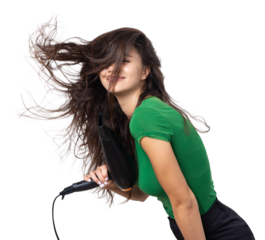 A cute young girl dressed in a green top dries her beautiful long silky hair with a hair dryer against a white background.