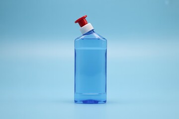Blue bottle with liquid product for cleaning and sanitizing on light background