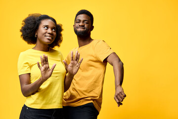 Happy African couple dancing joyfully in matching yellow outfits against a bright yellow background, showcasing vibrant emotions and dynamic movement