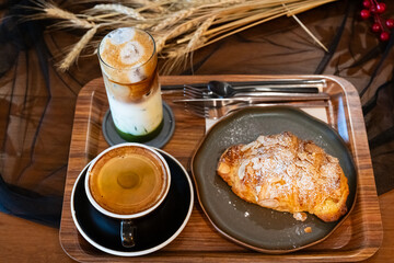 Close up delicious breakfast menu croissant and coffee cup on the wood table in the restaurant.