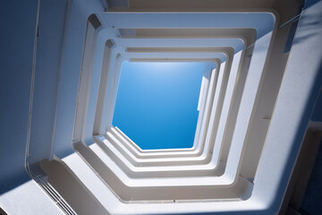 Ground-Up Courtyard Well View Of Concentric Apartment Balconies Framing Sky Rectangle, Morning Laundry Shadows, Ultra-Wide Architectural Geometry